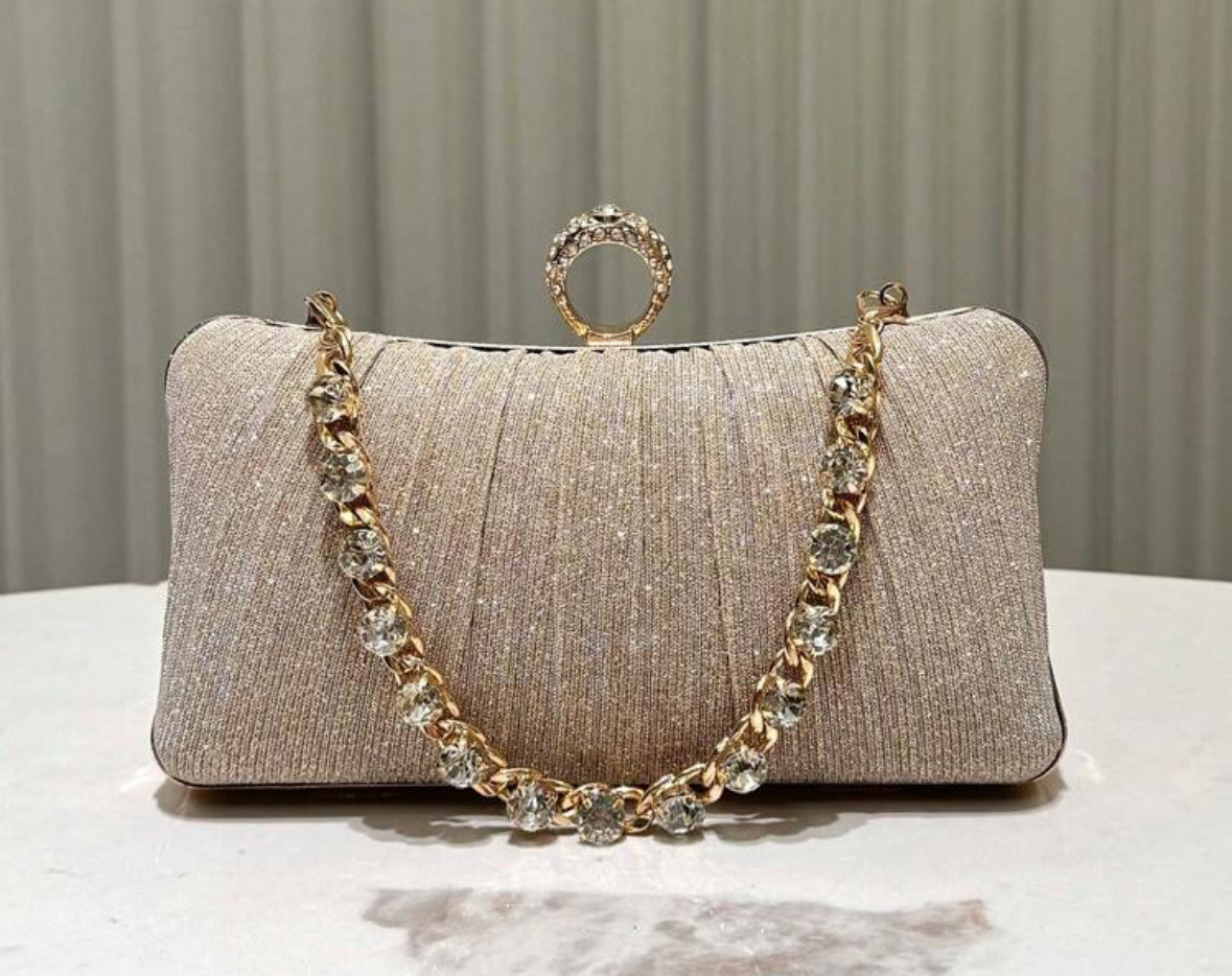 Champagne kleurige clutch met slot in de vorm van een gouden ring met diamanten voorzien van een gouden hengsel met diamanten