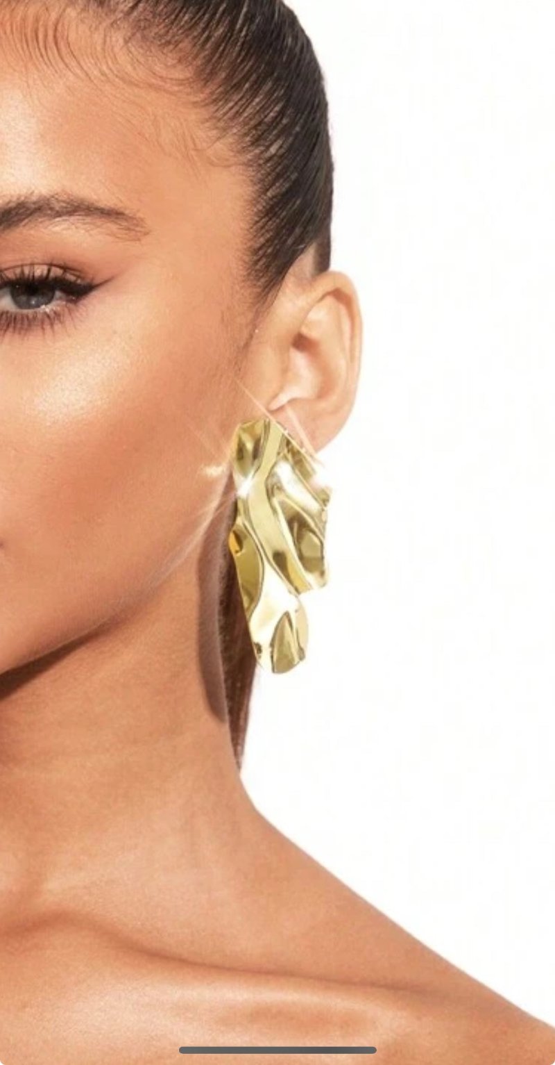 Vrouw met on the rocks oorbellen goudkleurig met steenstructuur vrouwelijk sexy sieraad