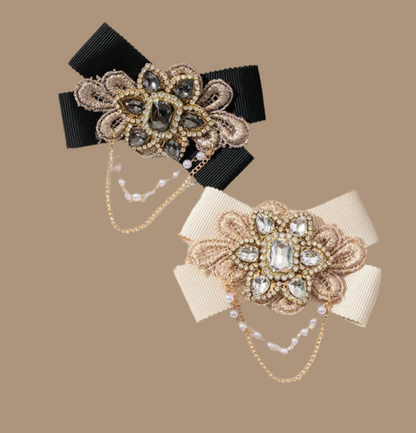 Broche in strikvorm met diamanten bloem en kettingen 