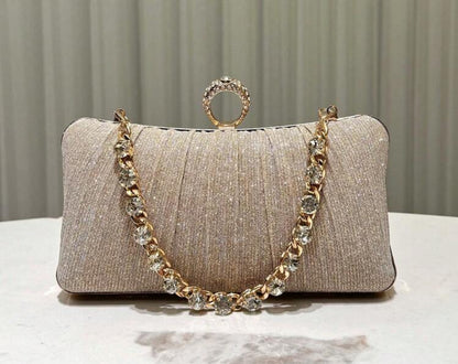 Champagne kleurige clutch met slot in de vorm van een gouden ring met diamanten voorzien van een gouden hengsel met diamanten