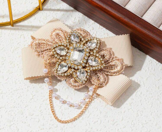 Broche in strikvorm met diamanten bloem en kettingen 